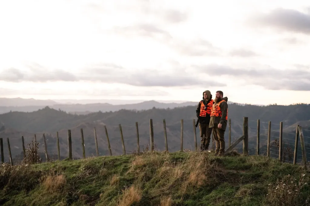 Two Hunt for Good volunteers on a hillside at sunrise